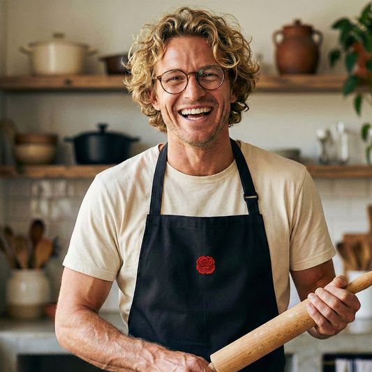 homme souriant dans une cuisine tenant un rouleau à patisserie et portant un tablier de cuisine célébrant les noces de coquelicot