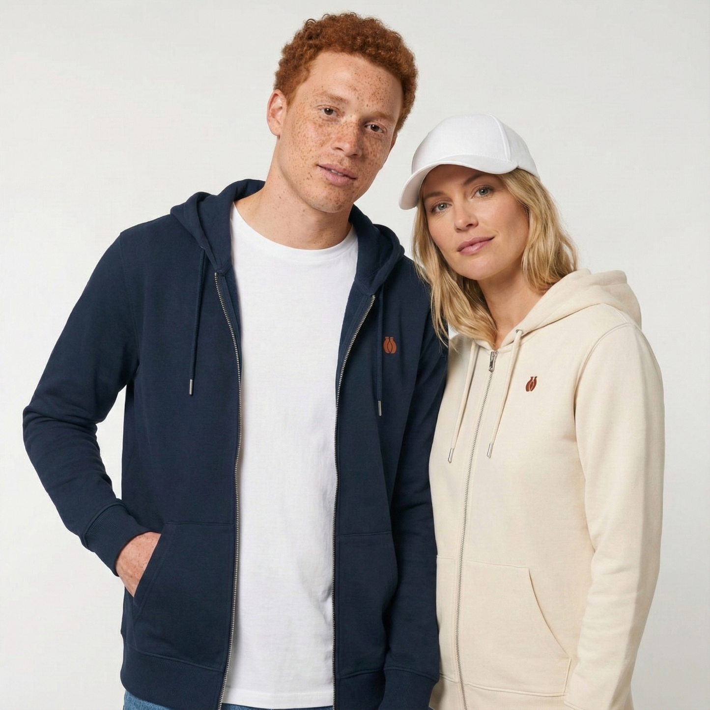 un homme et une femme portent un hoodie zippé unisexe floqué avec un logo représentant les noces d'argile