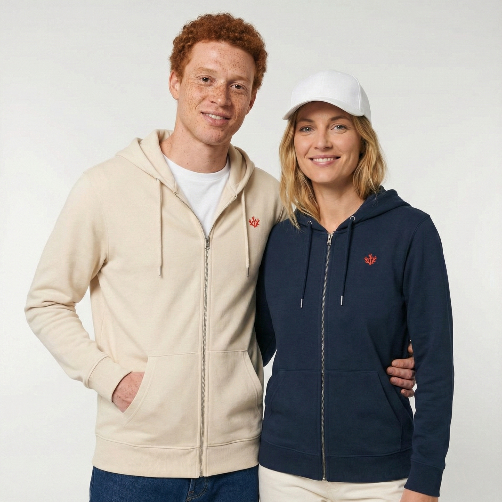 un homme et une femme portent un hoodie zippé unisexe floqué avec un logo représentant les noces de corail