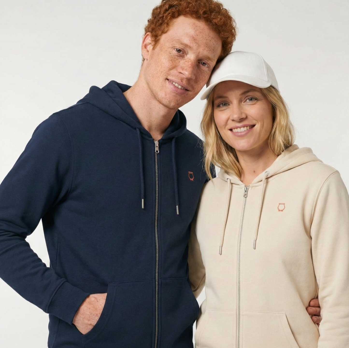un homme et une femme portent un hoodie zippé unisexe floqué avec un logo représentant les noces de cuivre