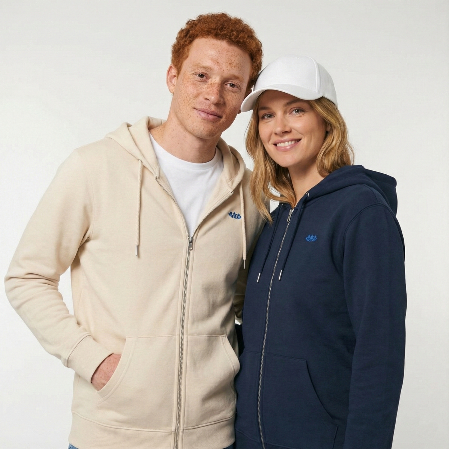 un homme et une femme portent un hoodie zippé unisexe floqué avec un logo représentant les noces de faience