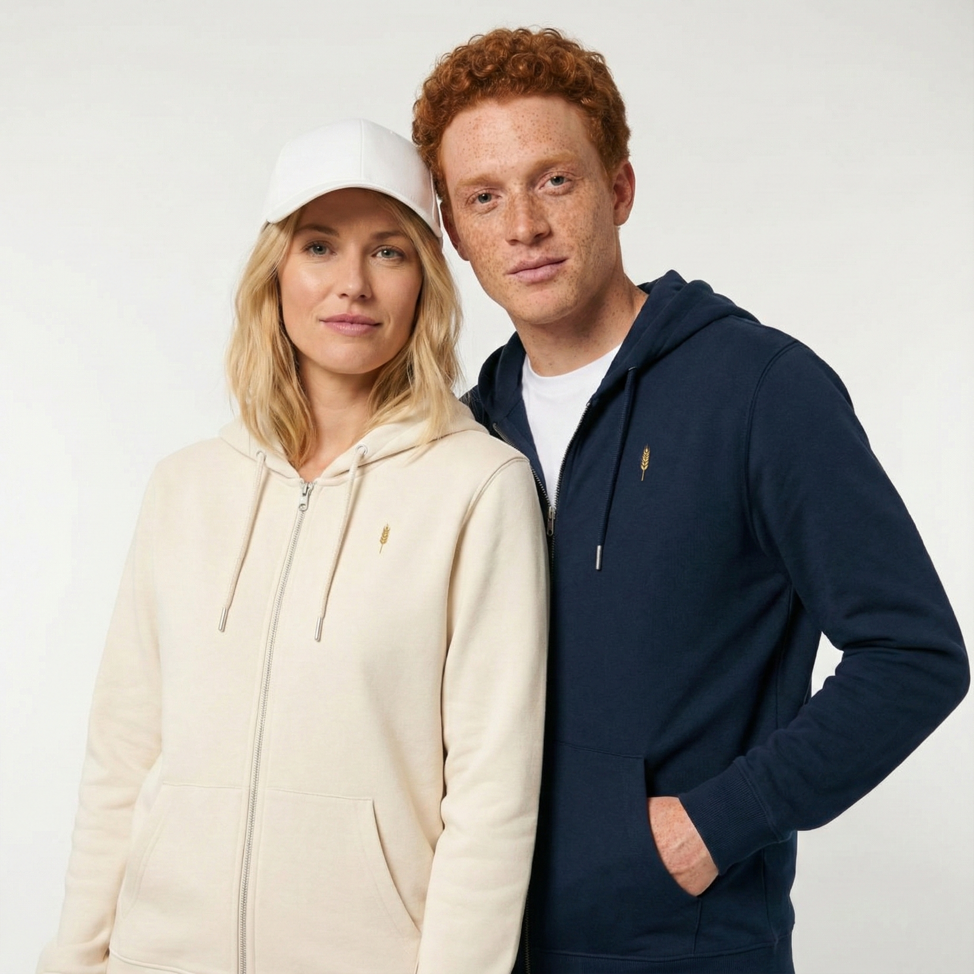 un homme et une femme portent un hoodie zippé unisexe floqué avec un logo représentant les noces de froment