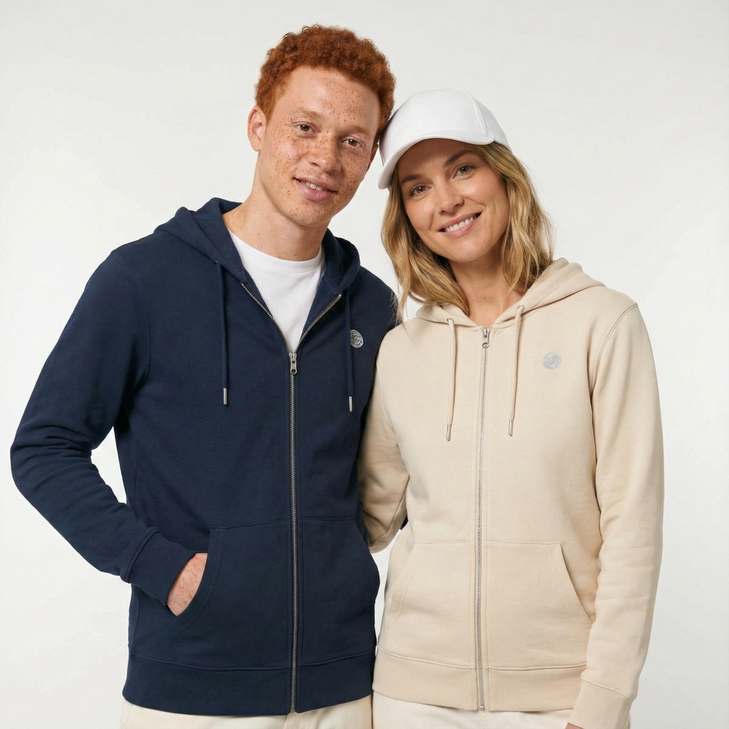 un homme et une femme portent un hoodie zippé unisexe floqué avec un logo représentant les noces de laine