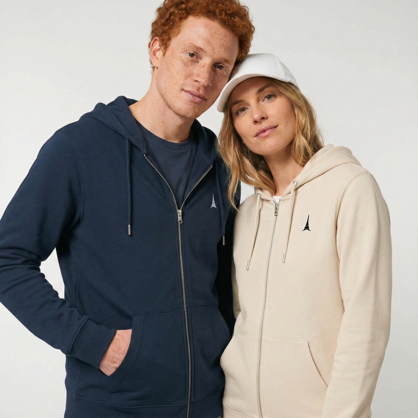 un homme et une femme portent un hoodie zippé unisexe floqué avec un logo représentant les noces de plomb