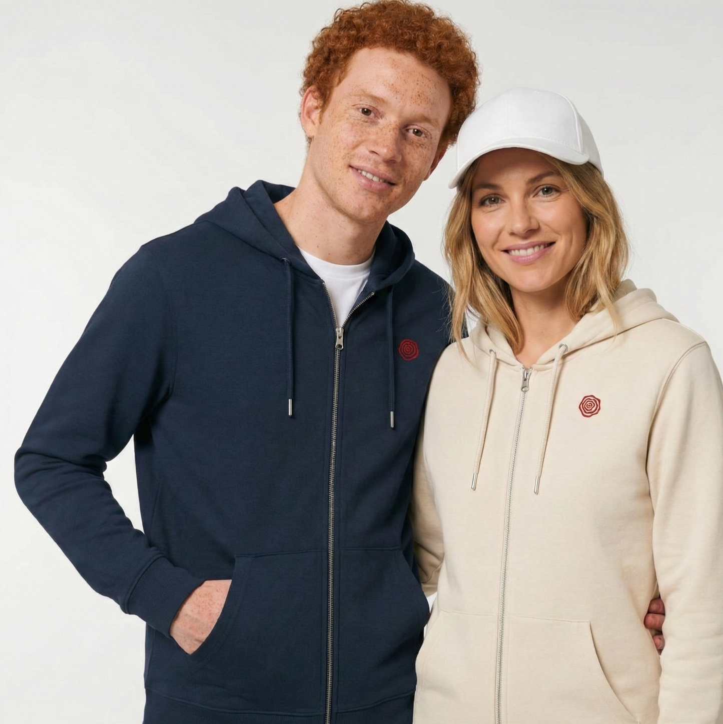 un homme et une femme portent un hoodie zippé unisexe floqué avec un logo représentant les noces de rose